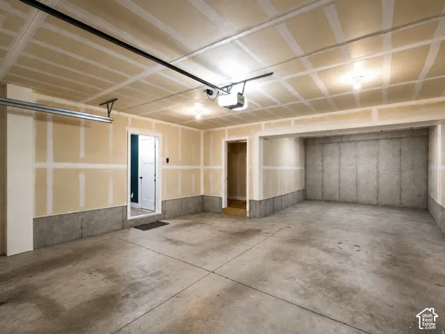 Spacious garage with concrete flooring, exposed drywall, overhead lighting, and an automatic garage door opener