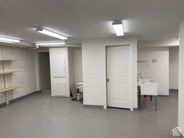 Utility space featuring a laundry sink, overhead fluorescent lighting, and built-in shelving