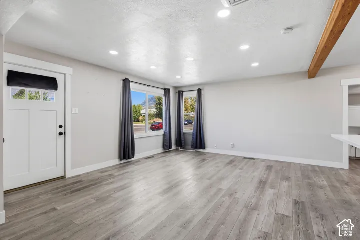Recessed ceiling lighting, wood-finish flooring, white paneled door with glass inserts, exposed wood beam, and a white countertop extension