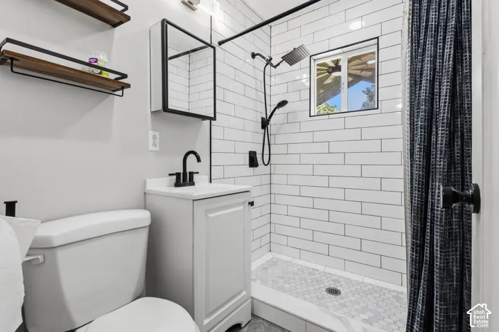 Subway tile shower with hexagonal tile flooring, matte black fixtures, white vanity with integrated sink, and an integrated wall cabinet with mirror