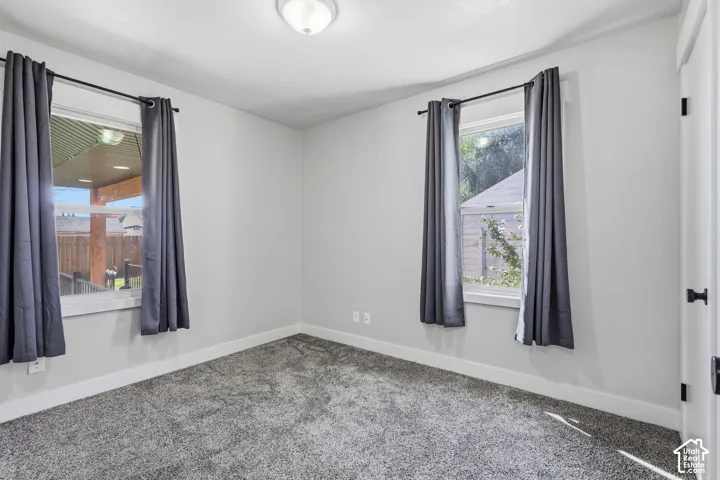 Plush gray carpeting, neutral wall palette, and two windows providing exterior light