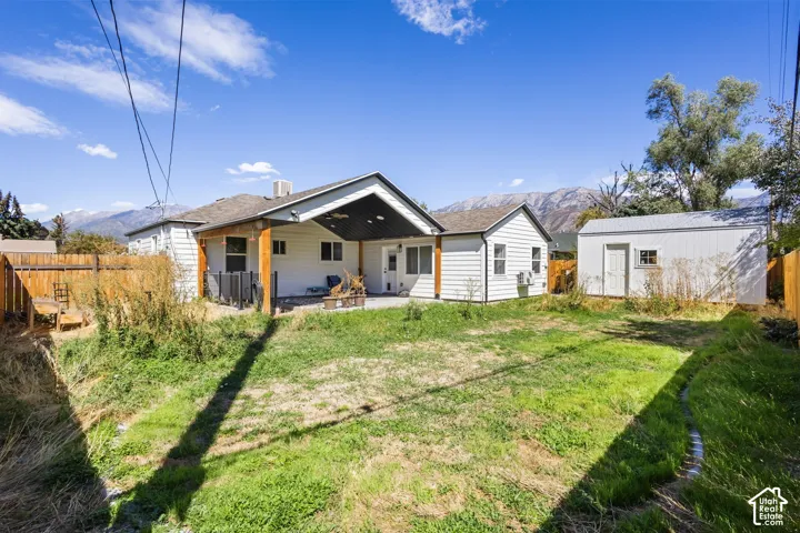 Rear exterior with covered patio, wood fencing, and detached storage shed