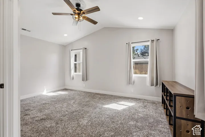 Vaulted ceiling featuring a ceiling fan with light fixture, recessed lighting, and carpet flooring