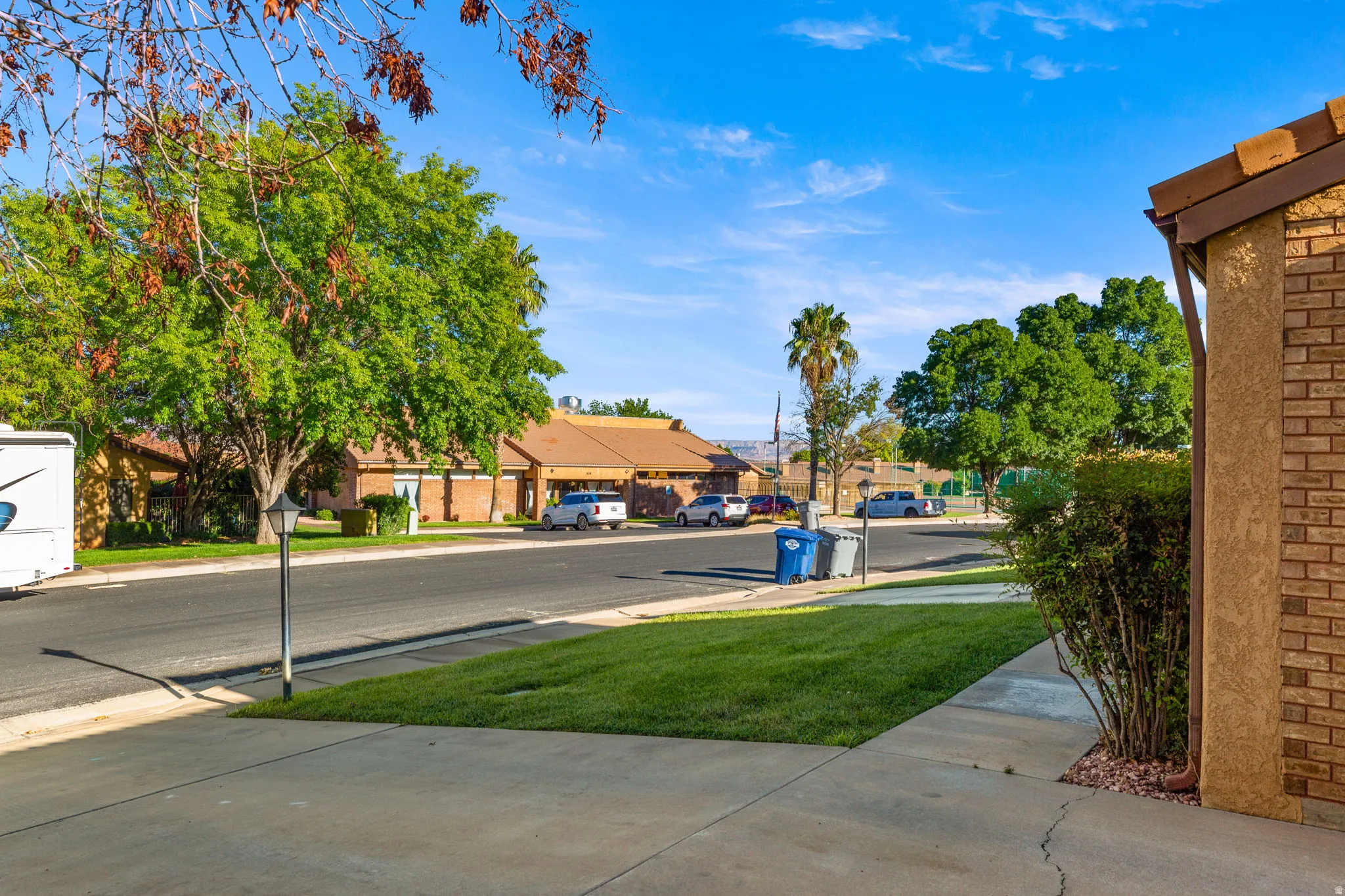 Manicured front lawn with mature trees and concrete walkways