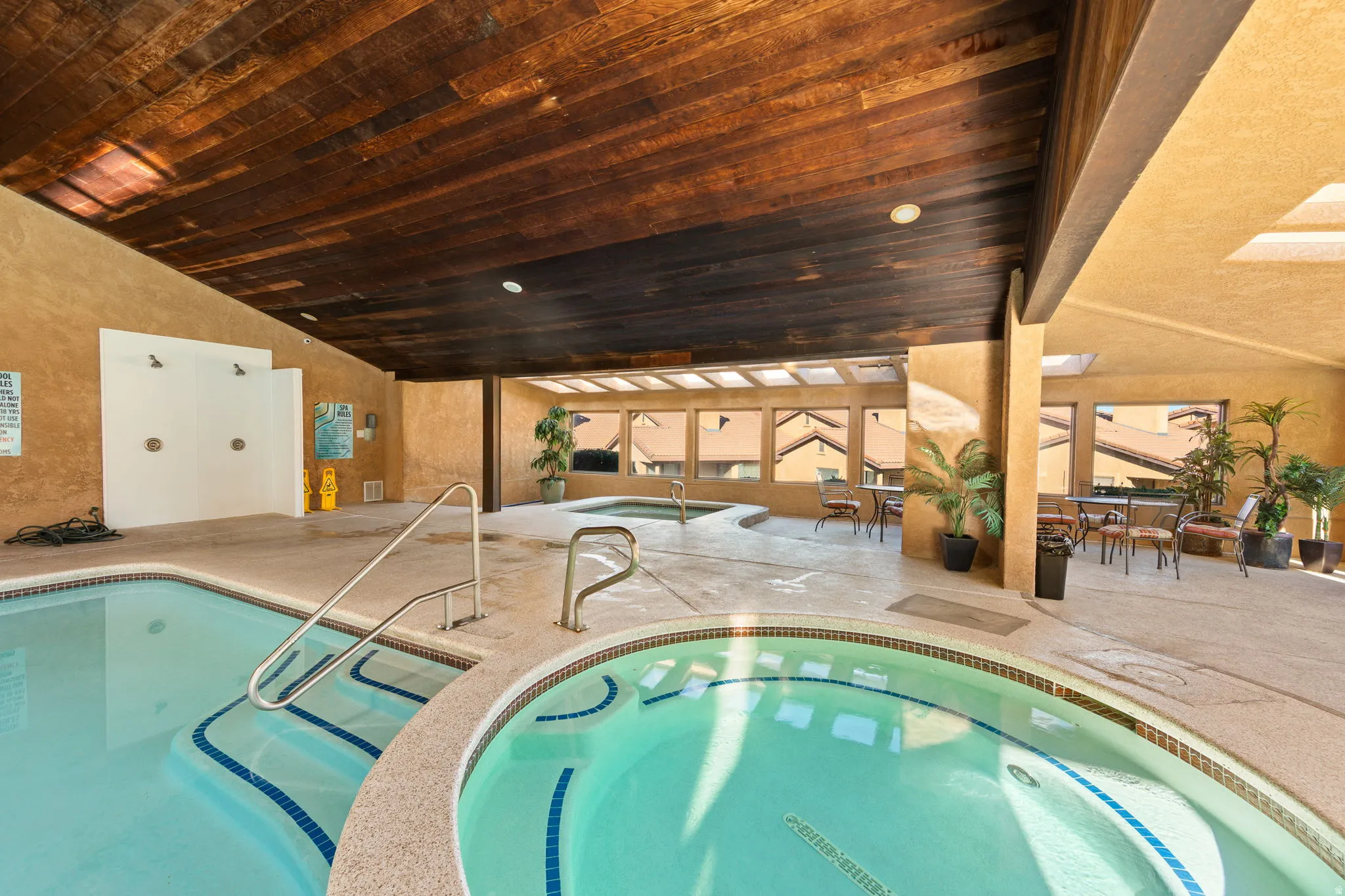 Indoor pool with integrated spa, wood-finish ceiling, and multiple skylights