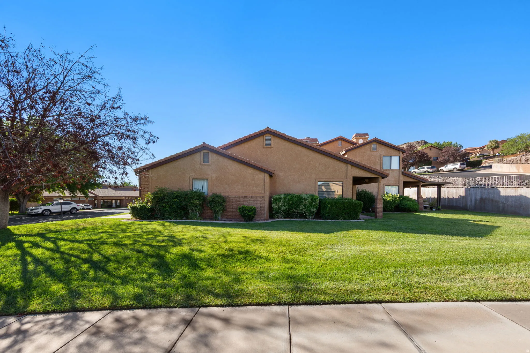 Expansive grassy yard with mature landscaping, stucco exterior, brick accent features.