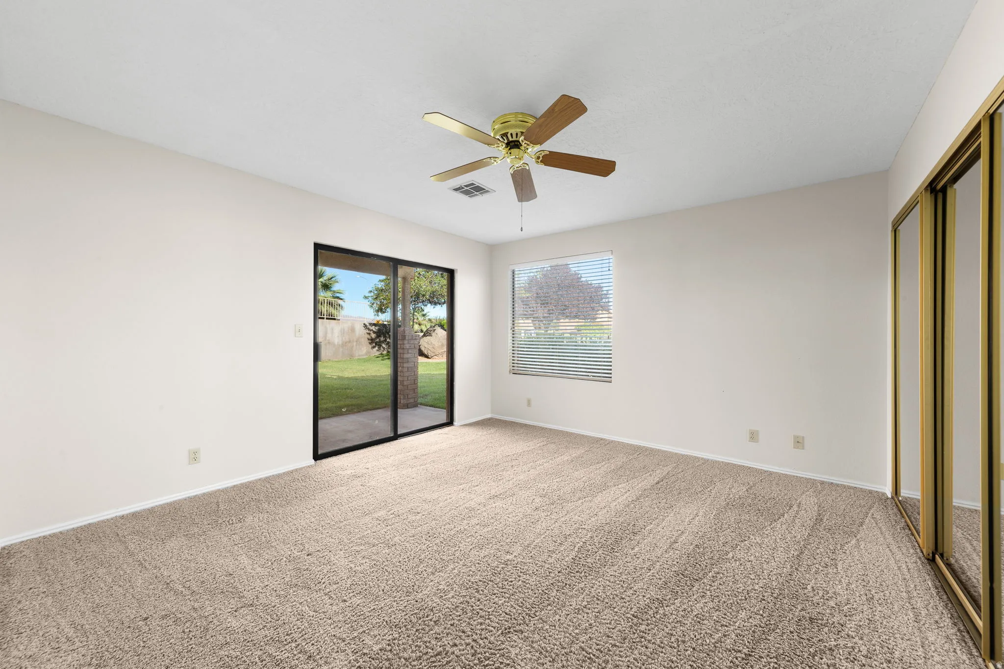 Primary Room. Wall-to-wall carpeting, sliding glass patio door, ceiling fan, and mirrored closet doors