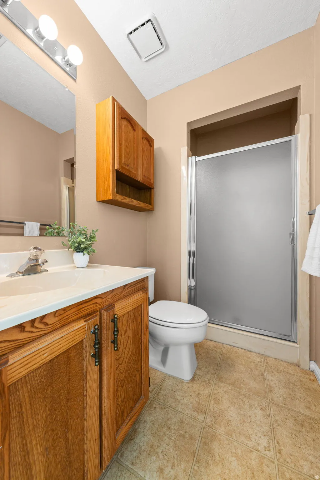 Wood-finish vanity with white countertop, and glass-enclosed shower