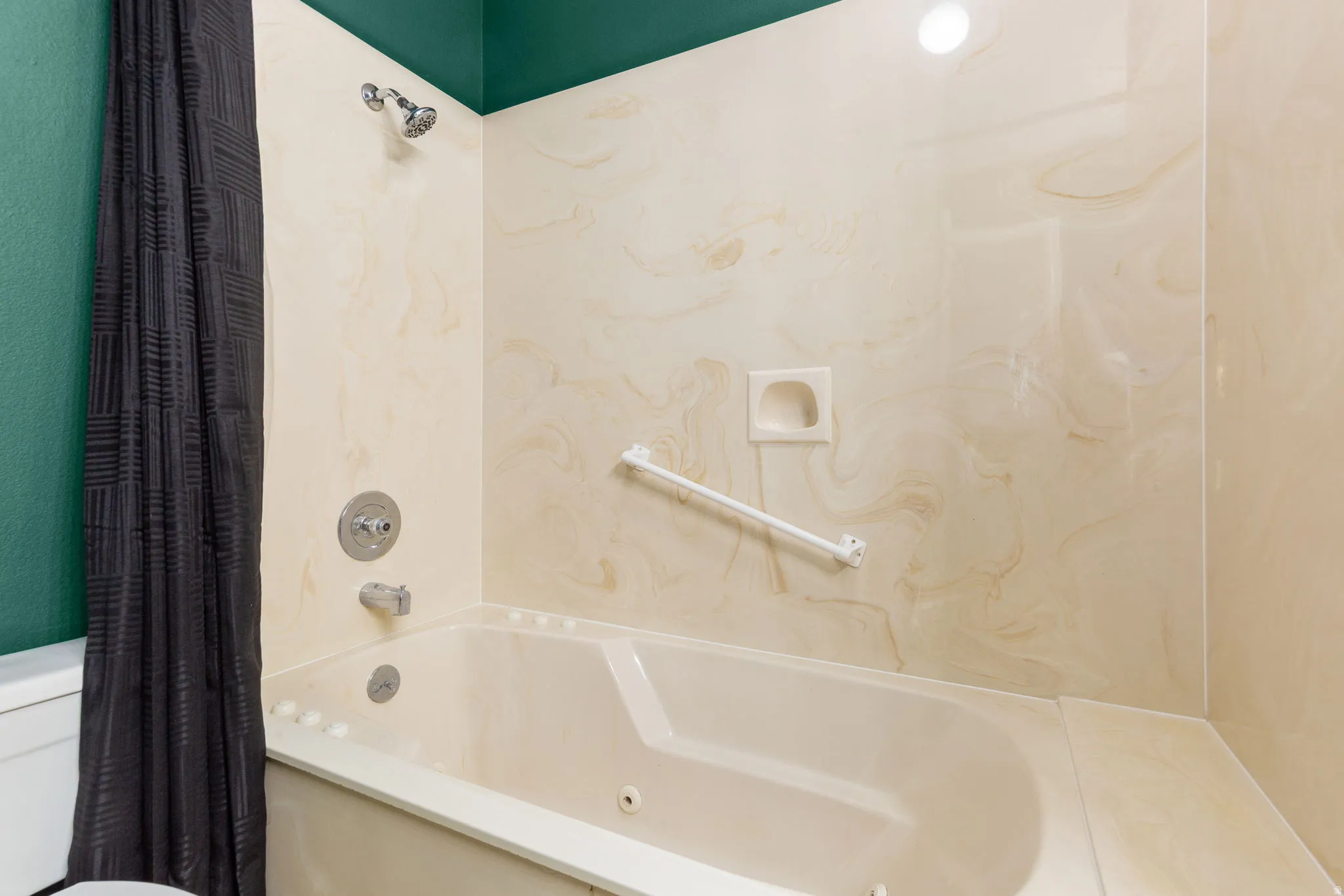 Built-in tub with a grab bar, integrated shower, and wall-mounted shower head