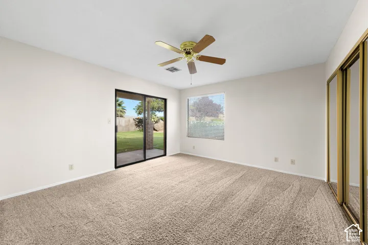 Primary Room. Wall-to-wall carpeting, sliding glass patio door, ceiling fan, and mirrored closet doors