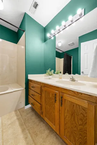 Wood-finish vanity with integrated sink, a large wall mirror.