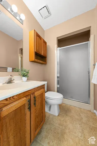 Wood-finish vanity with white countertop, and glass-enclosed shower