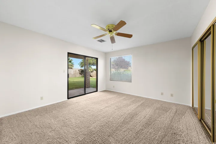 Primary Room. Wall-to-wall carpeting, sliding glass patio door, ceiling fan, and mirrored closet doors
