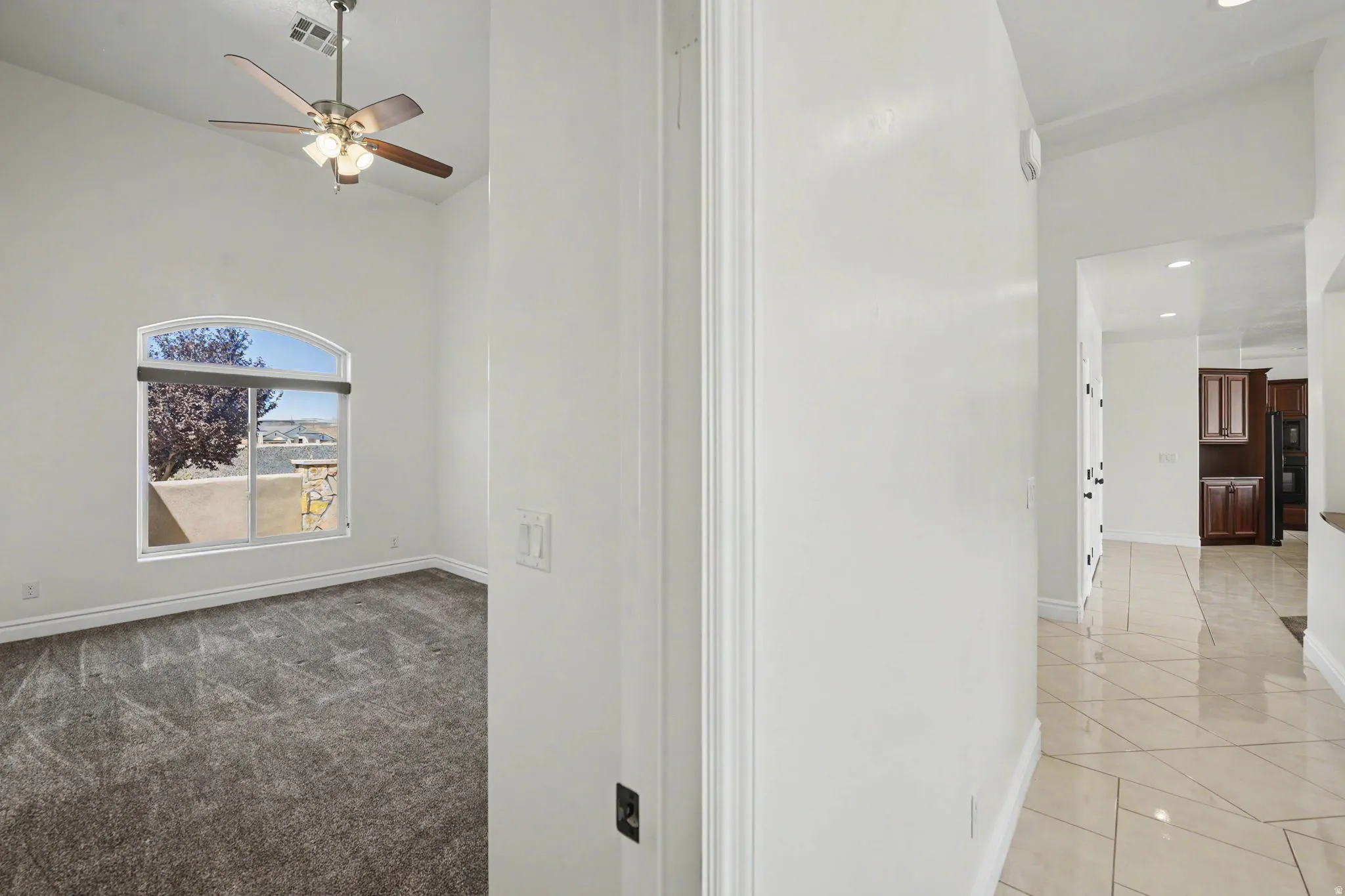 Arched window with roller shade and carpeted flooring