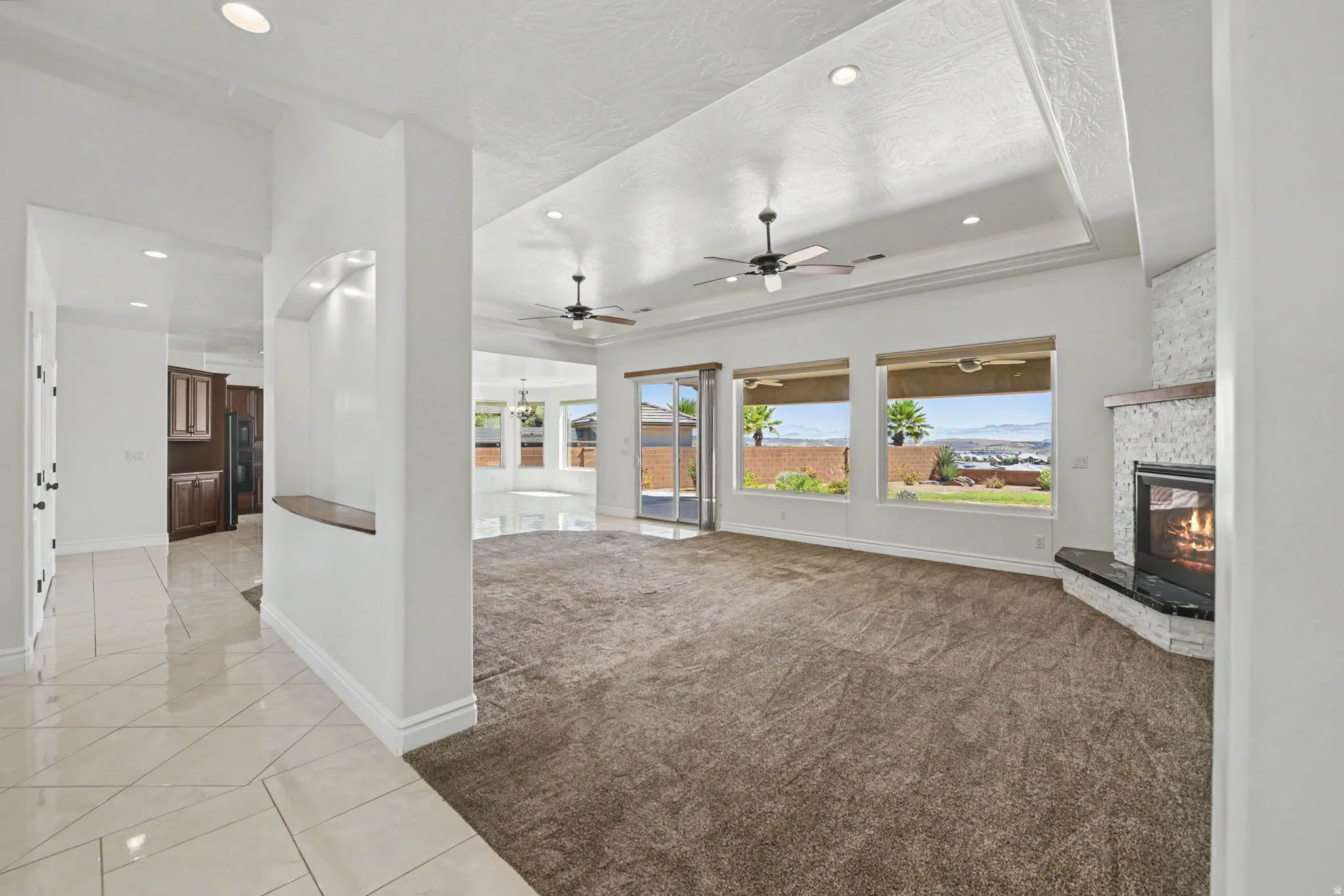 Recessed lighting, tray ceiling, ceiling fans, built-in fireplace, and expansive windows