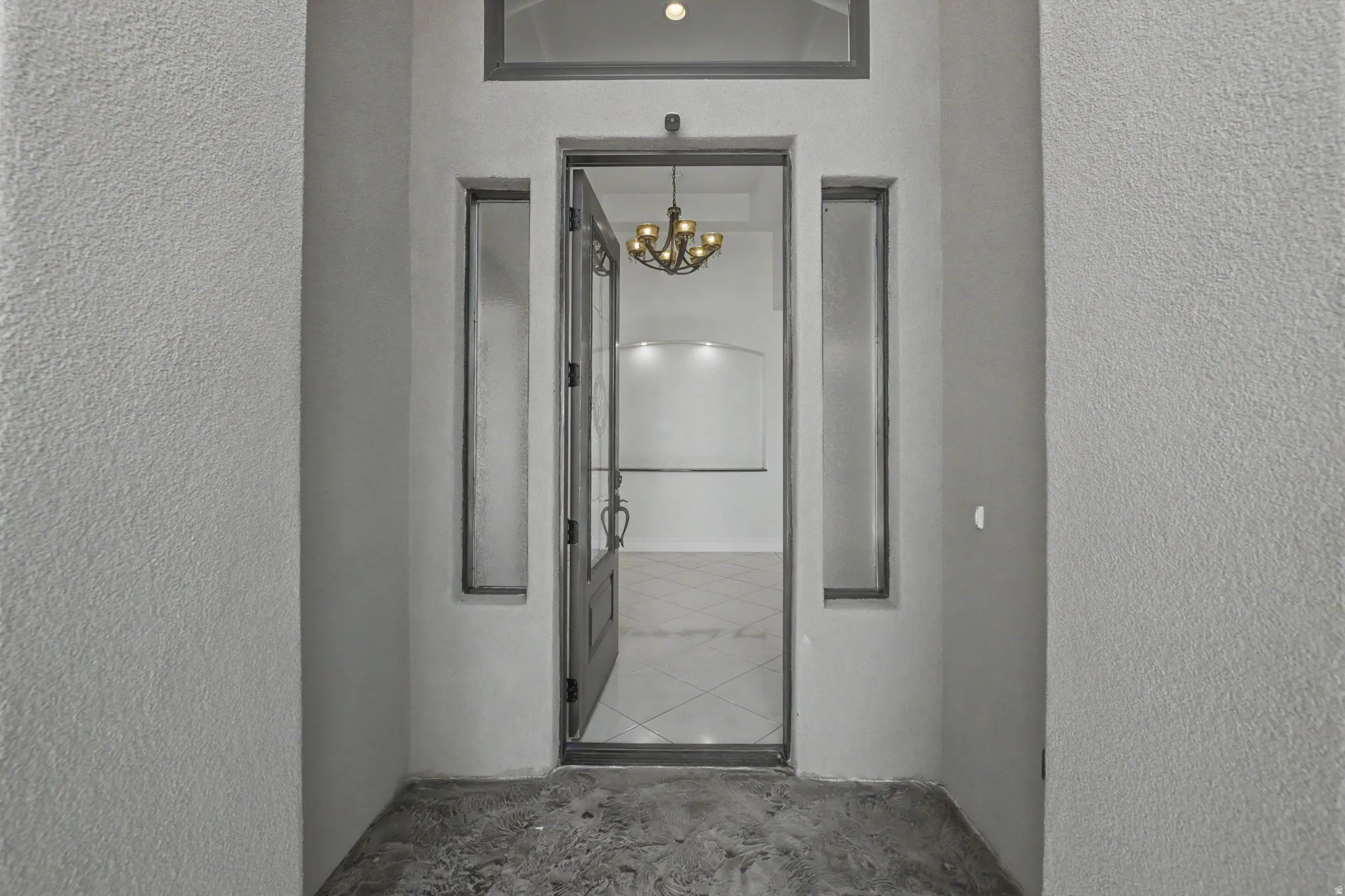 Entryway featuring a decorative transom window, sidelight windows, and an ornate chandelier