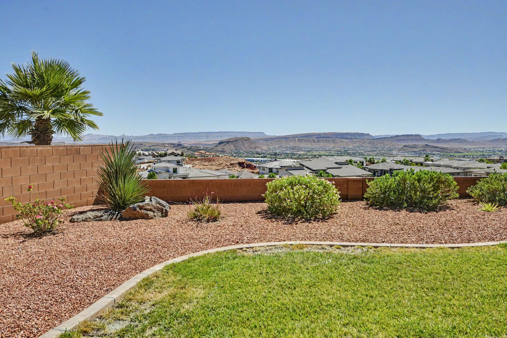 Manicured lawn with a decorative rock garden, mature palm tree, and a block retaining wall