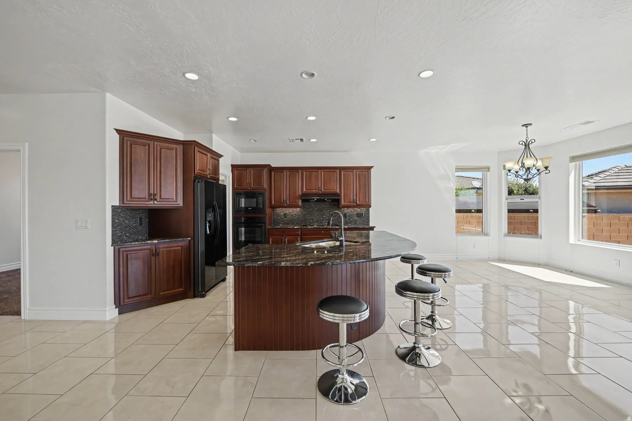 Recessed lighting, wood cabinetry, built-in double ovens, a kitchen island with a breakfast bar, and tile flooring