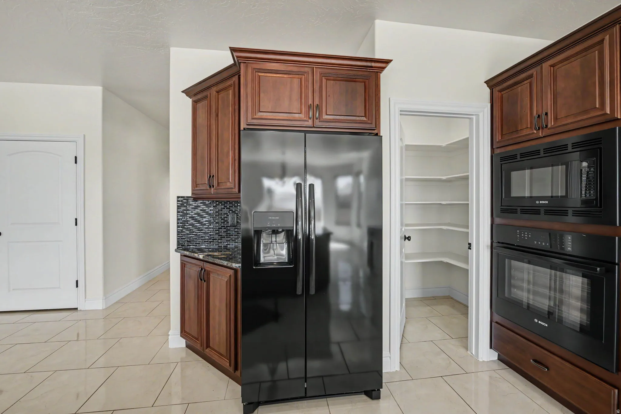 Kitchen featuring wood cabinetry, stainless steel refrigerator, built-in microwave, wall oven, and a walk-in pantry