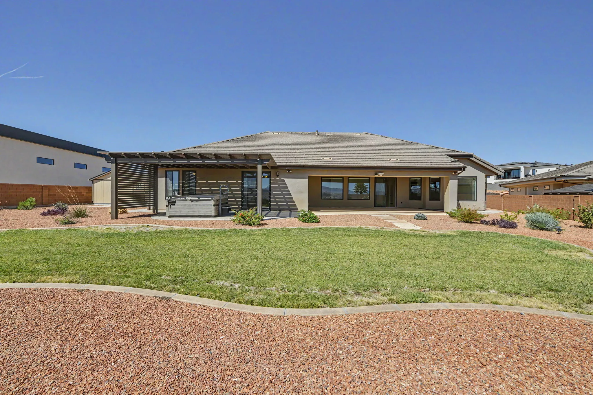 Expansive backyard featuring a manicured lawn, a built-in hot tub, an attached pergola, and a covered patio area