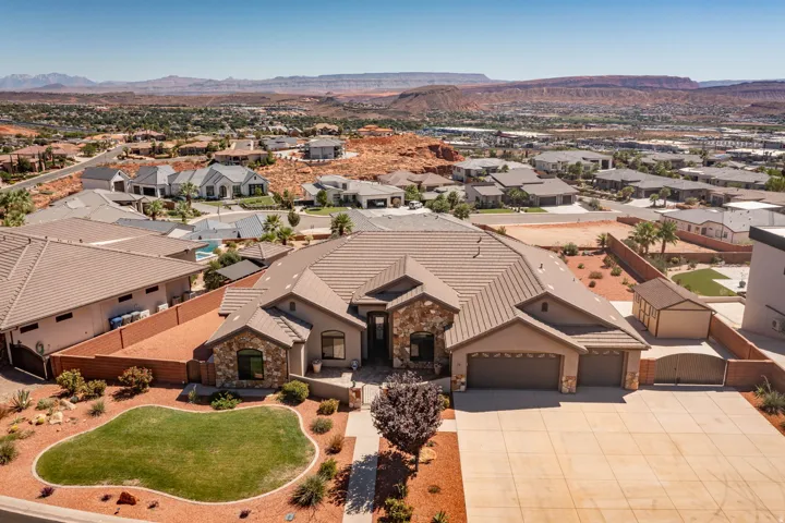Stone and stucco exterior with a multi-car garage, concrete driveway, and a front yard featuring a lawn and xeriscaping