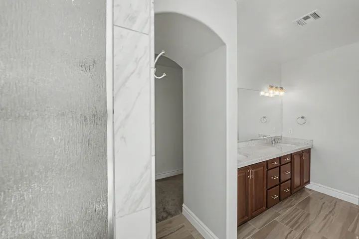 Dual vanity with integrated sinks, wood-finish cabinetry, and a framed mirror