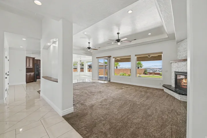 Recessed lighting, tray ceiling, ceiling fans, built-in fireplace, and expansive windows