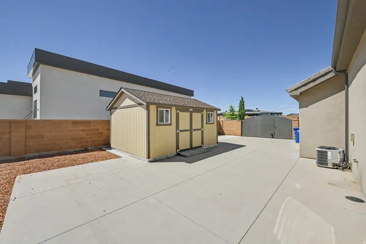 Detached storage shed, concrete patio, block wall perimeter, and a substantial gate