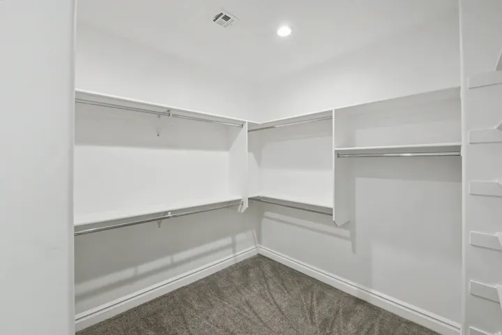 Walk-in closet with carpet flooring, recessed lighting, and integrated shelving and hanging rods