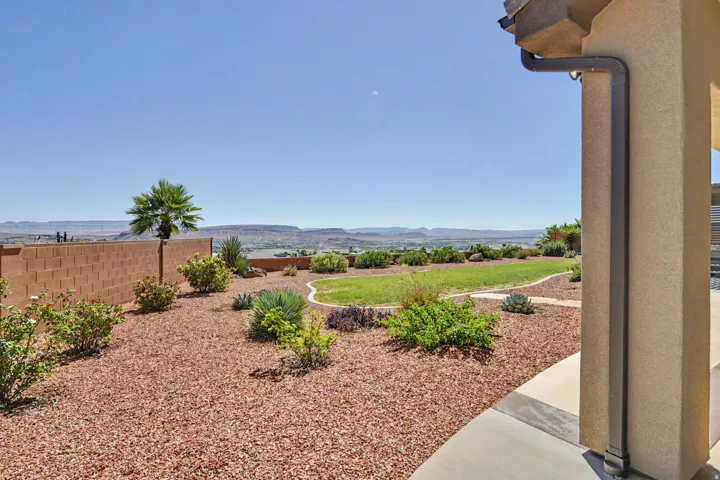 Expansive backyard featuring a manicured lawn, established landscaping, and a block wall perimeter