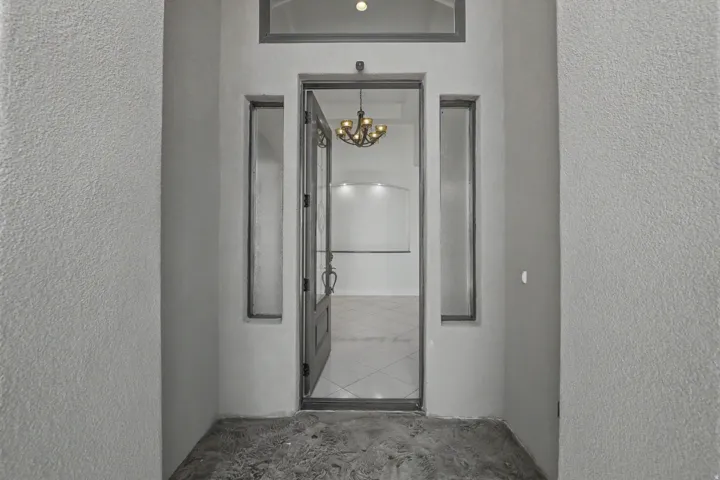 Entryway featuring a decorative transom window, sidelight windows, and an ornate chandelier