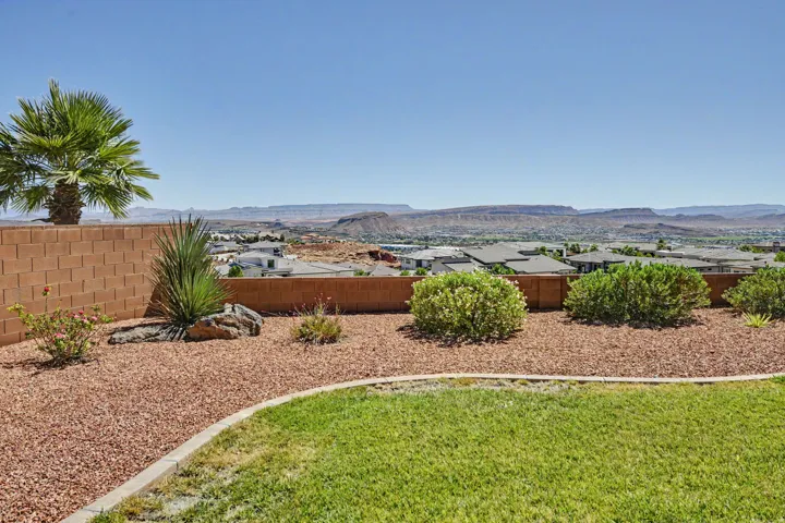 Manicured lawn with a decorative rock garden, mature palm tree, and a block retaining wall