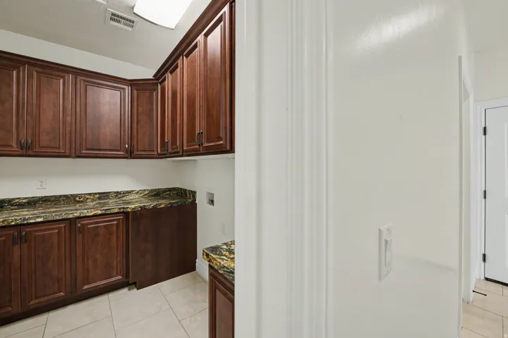 Built-in wood cabinetry with crown molding, stone countertops, and tile flooring
