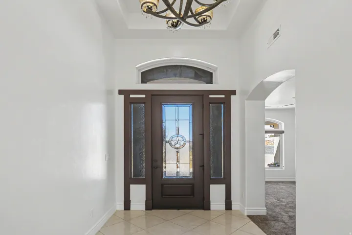 Entryway featuring a decorative transom window, leaded glass front door, side panel windows, and a coffered ceiling with an attached chandelier