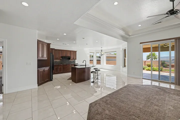 Open-concept living space featuring high ceilings with recessed lighting, tile flooring, a kitchen island with seating, and a sliding glass door