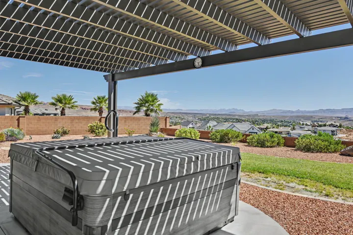 Patio with an attached pergola, built-in spa, expansive desert landscaping, and distant mountain scenery