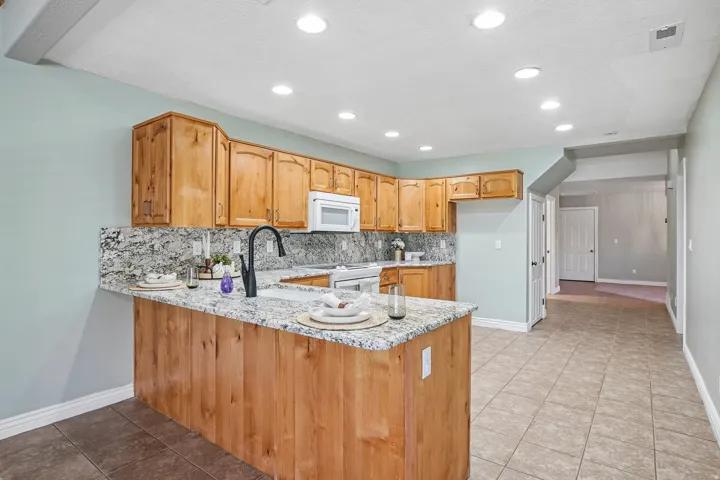 Kitchen featuring wood cabinetry, light-toned stone countertops, and a built-in microwave
