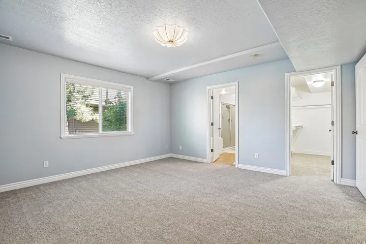Carpeted room with a single window, overhead lighting, and two doorways leading to additional interior spaces