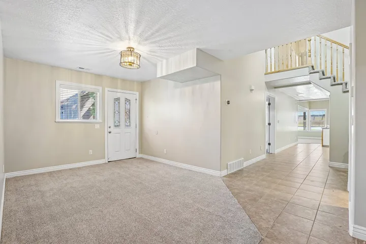 Entryway featuring a decorative front door with frosted glass inserts, a carpeted living space, and a tiled hallway