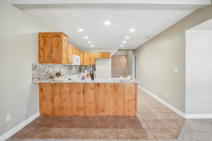 Kitchen featuring wood cabinetry, granite countertops, tile backsplash, built-in appliances, and recessed lighting