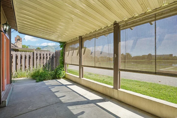 Covered patio with concrete flooring, exterior wall lantern, and retractable shade screens