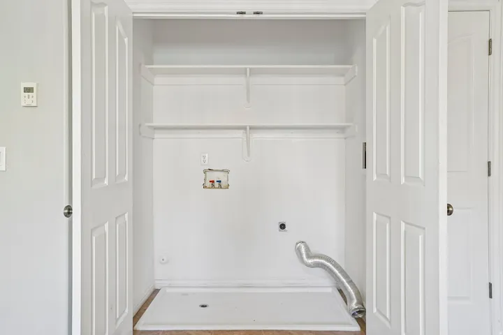Laundry closet with bifold doors, utility hookups, and built-in shelving