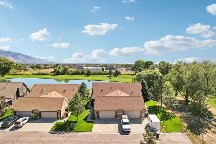 Property featuring a tranquil pond, distant mountains, mature trees, and a manicured lawn