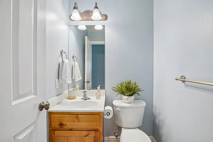 Vanity with wood-finish cabinetry, white countertop, and integrated sink