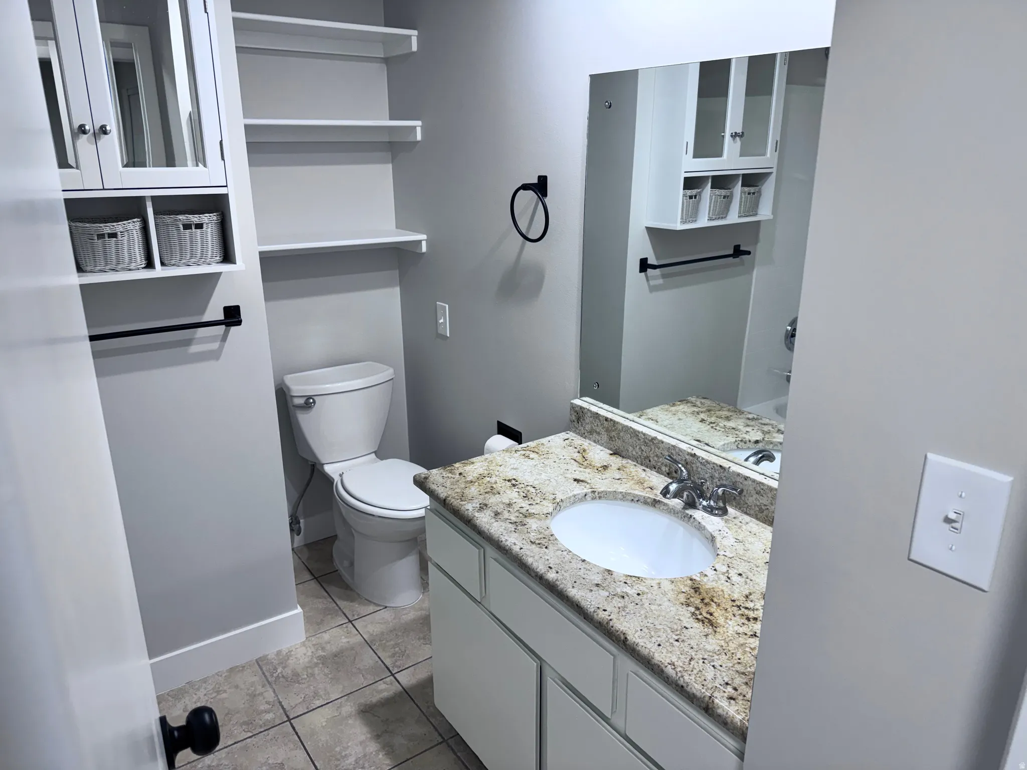 Vanity with a granite-finish countertop, undermount sink, and chrome faucet