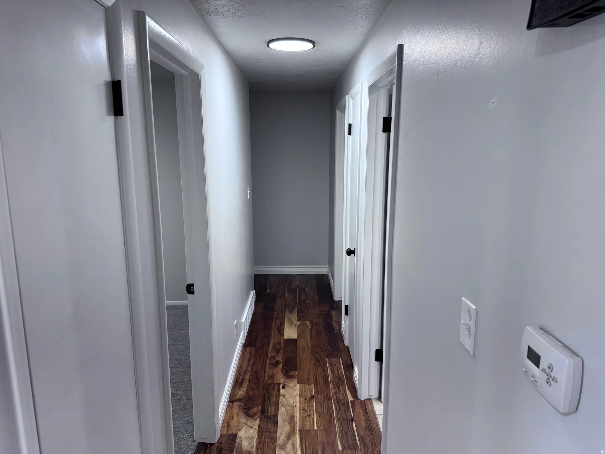 Hallway featuring wood-finish flooring, light gray wall paint, white trim, and recessed lighting