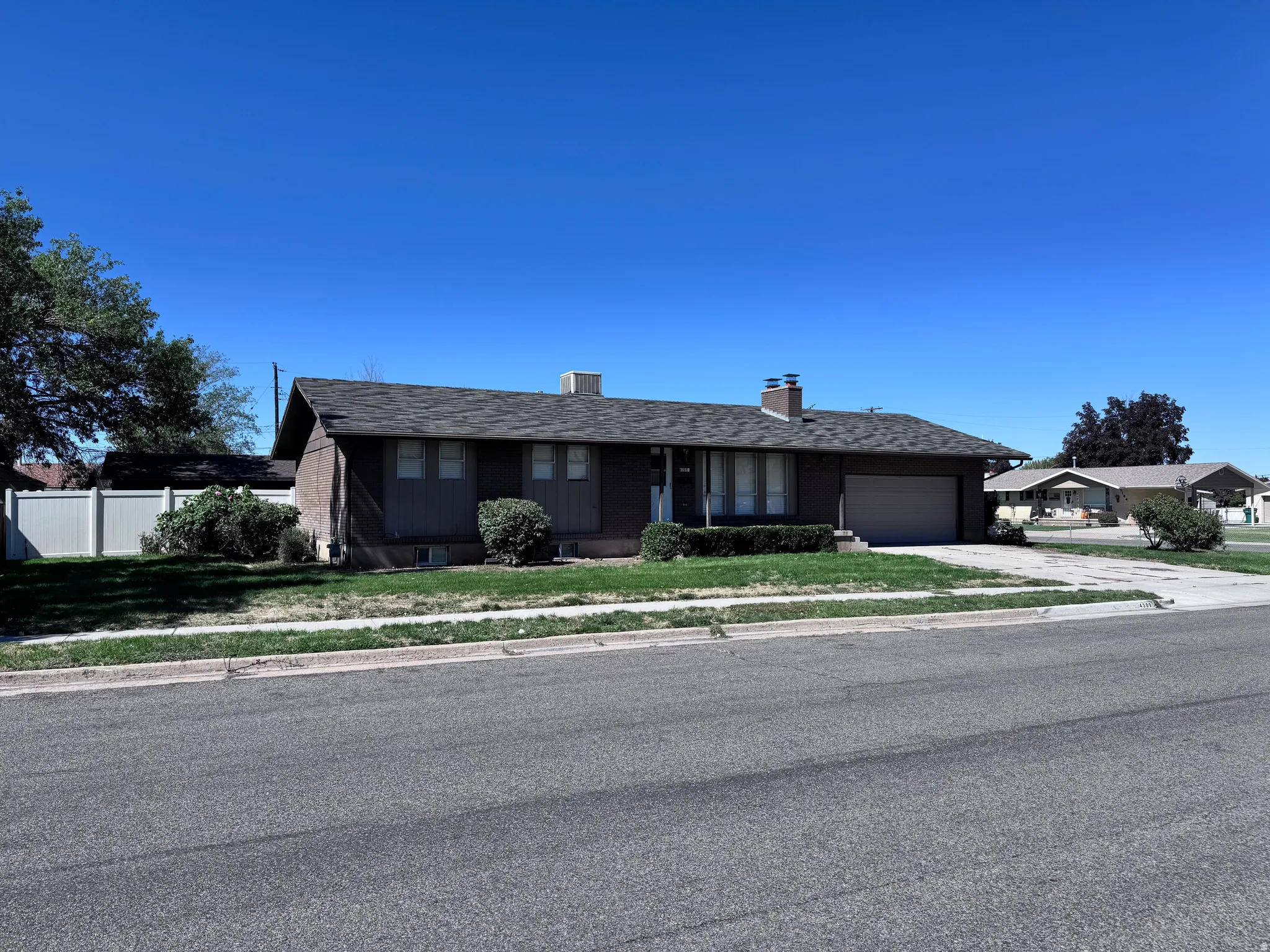 Ranch-style residence featuring a dark shingle roof, attached single-car garage, and a front lawn with mature shrubbery