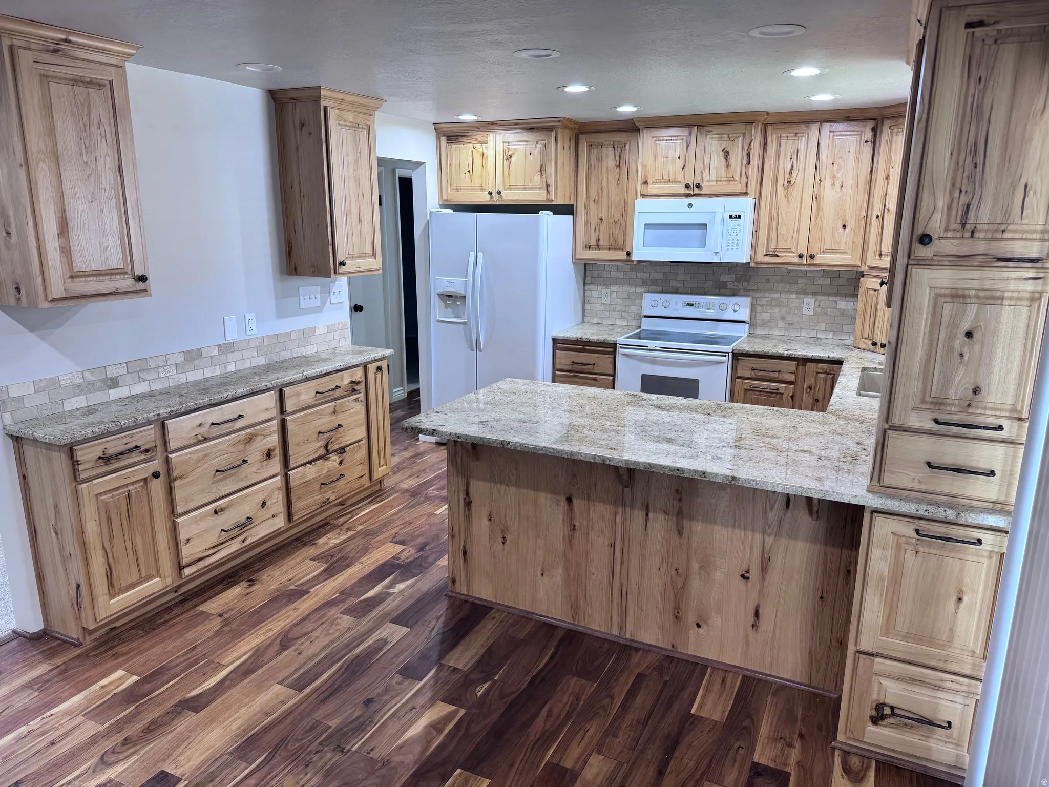 Kitchen featuring wood cabinetry, light-toned countertops, a mosaic tile backsplash, wood-finish flooring, and recessed lighting