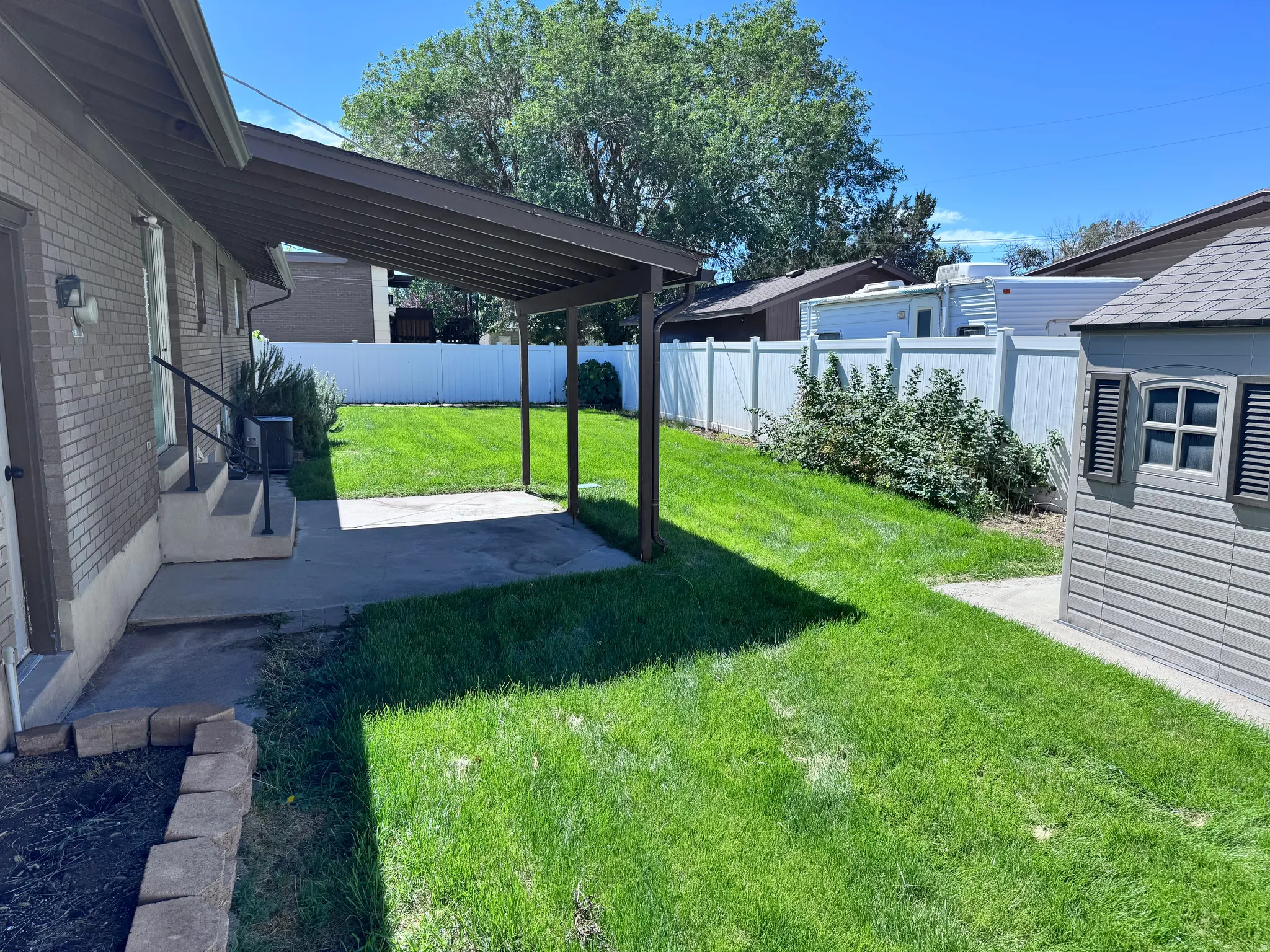 Rear yard with a covered patio, brick exterior, and a white privacy fence