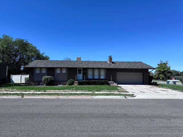 Ranch-style residence featuring a prominent front lawn, an attached garage, and a concrete driveway